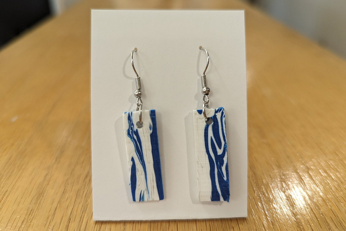 A pair of earrings made from 100% recycled post-consumer HDPE Products. Blue from detergent bottles and white from milk jugs.