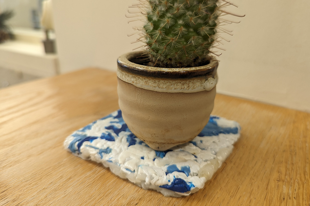 A small plant holder made from 100% recycled post-consumer products. Blue from detergent bottles and white from milk jugs.