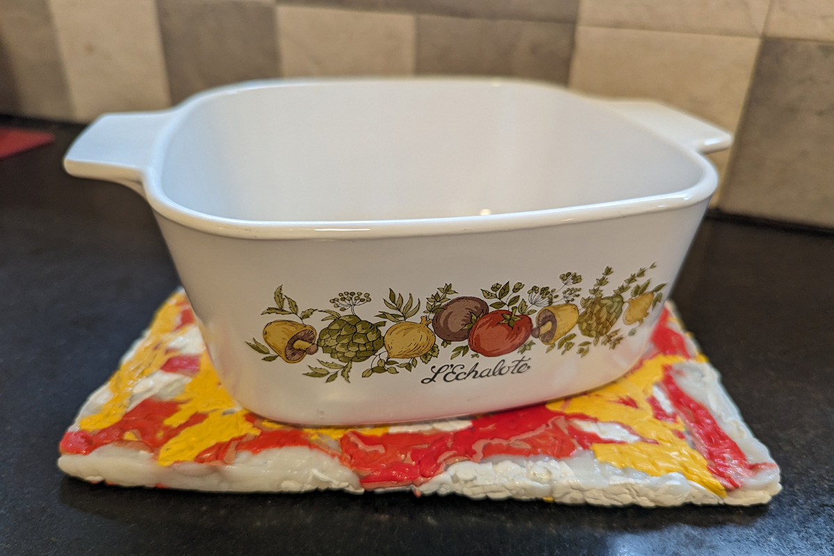A pot holder made from 100% recycled post-consumer HDPE Products. Orange and yellow from detergent bottles and white from milk jugs.